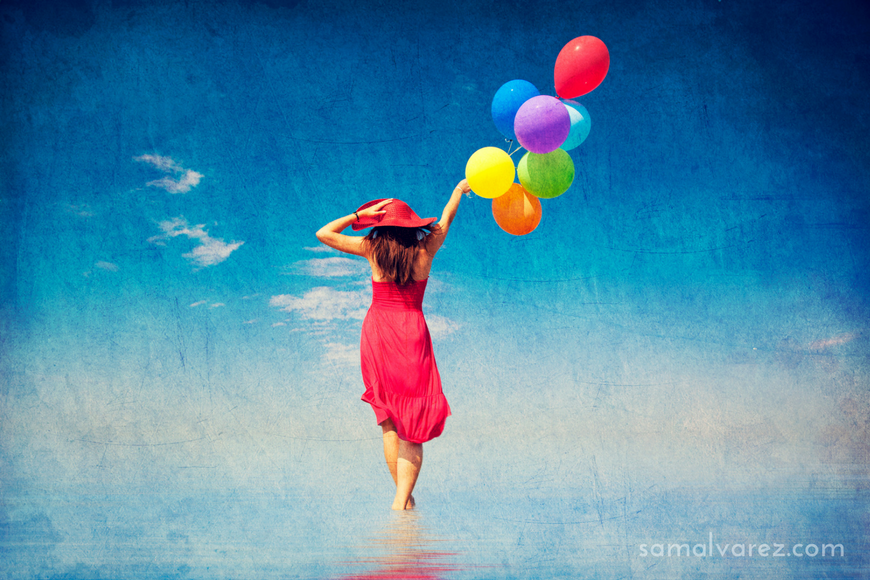 Brunette girl with colour balloons at coast